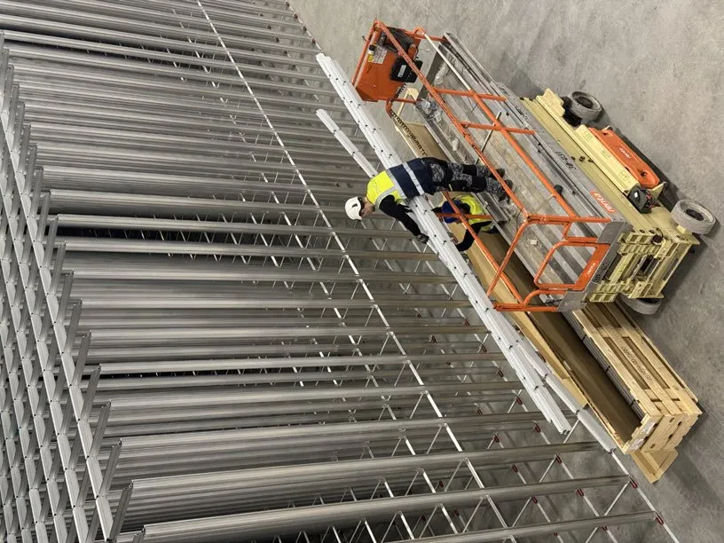 A worker on a scissor lift in a warehouse, seen from above